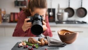 Fotógrafa de gastronomía capturando platos gourmet en un restaurante con luz natural para marketing visual profesional