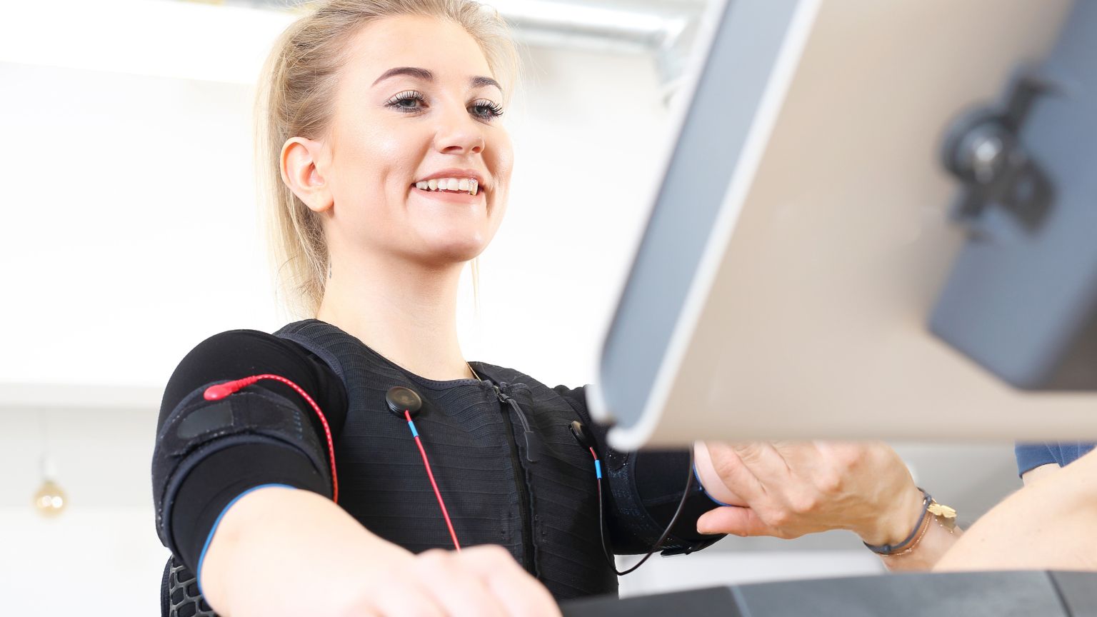 Persona entrenando con entrenador personal en sesión exprés con tecnología de resistencia adaptativa