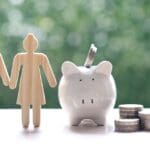 Pareja de personas mayores junto a hucha y monedas representando el ahorro a largo plazo con seguros de vida en España para 2026