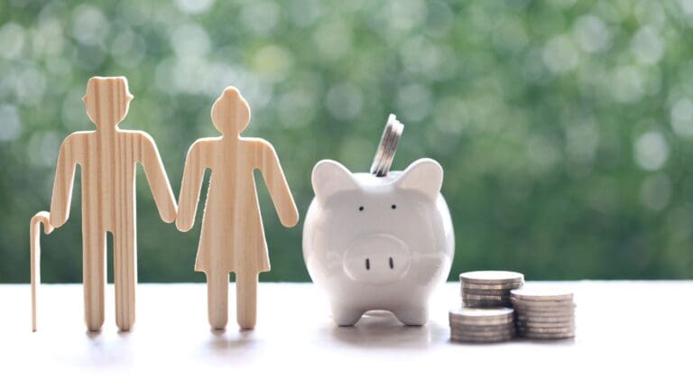 Pareja de personas mayores junto a hucha y monedas representando el ahorro a largo plazo con seguros de vida en España para 2026