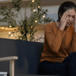 Persona sentada en un sofá con expresión pensativa, representando los primeros síntomas de ansiedad en su día a día.