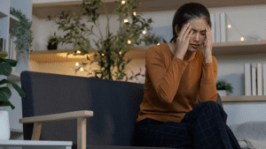 Persona sentada en un sofá con expresión pensativa, representando los primeros síntomas de ansiedad en su día a día.