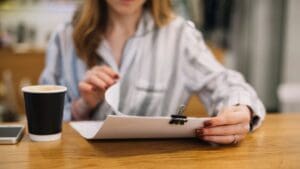 Autónomo revisando documentación en una cafetería moderna, rodeado de papeles y portátil, simbolizando dudas legales sobre licencias de actividad