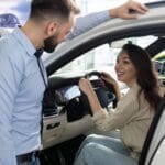 Persona revisando un coche de segunda mano en concesionario de Valladolid, inspeccionando interior y exterior del vehículo antes de comprar.