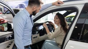 Persona revisando un coche de segunda mano en concesionario de Valladolid, inspeccionando interior y exterior del vehículo antes de comprar.