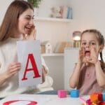 Niño sonriente recibiendo apoyo de una logopeda en casa