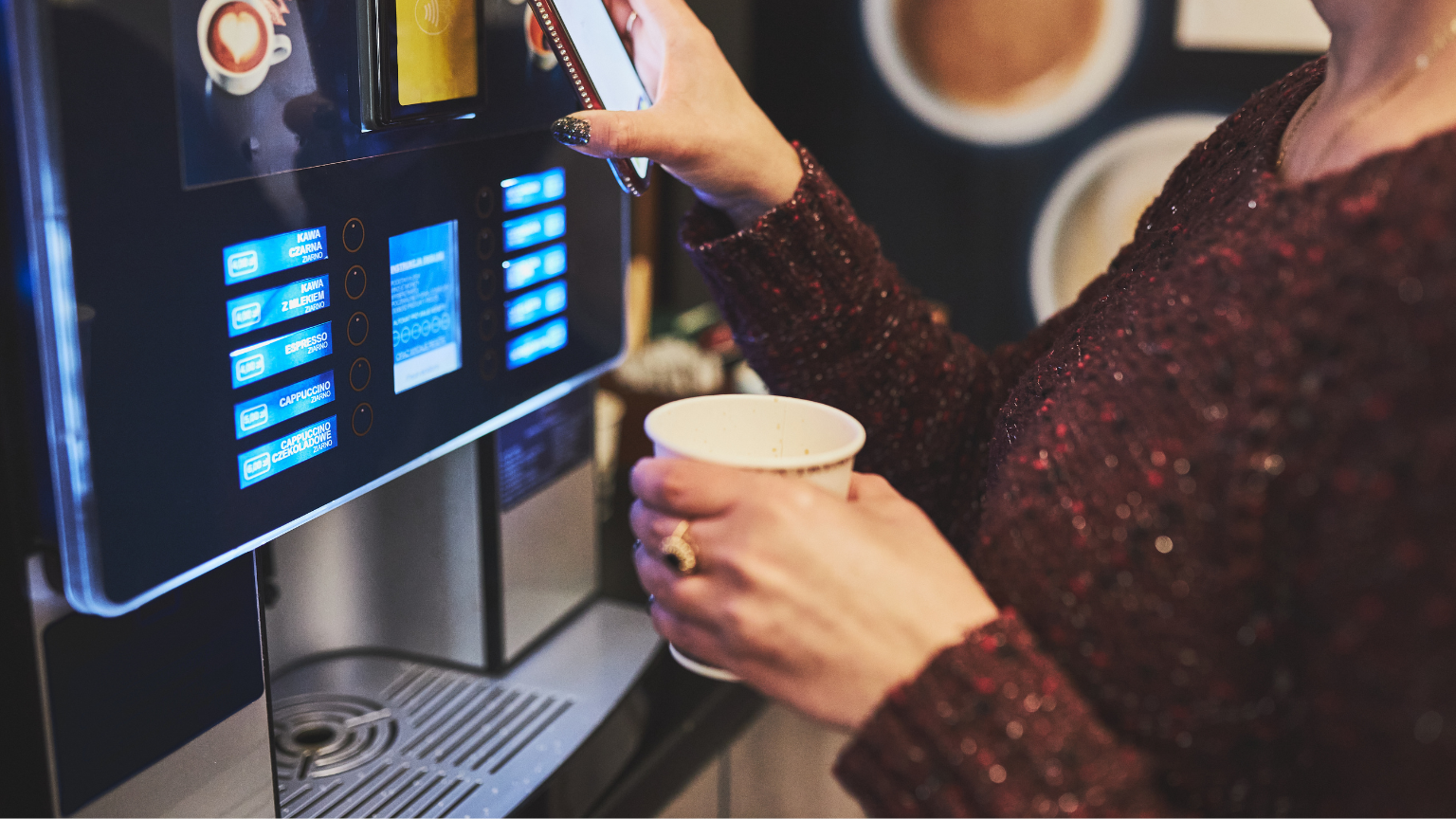 Empleados utilizando máquinas de café vending en una oficina moderna.