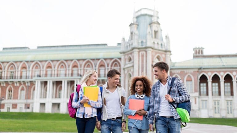 Grupo de estudiantes internacionales sonrientes en un campus universitario moderno.