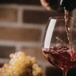 Copa de vino tinto siendo servida, representación de vinos premium en una tienda de vinos online