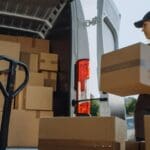 Empresa de logística integral gestionando transporte de mercancías con carga de paquetes en furgoneta de reparto