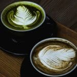 Comparativa visual matcha vs café mostrando ambas bebidas en taza sobre mesa clara