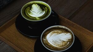 Comparativa visual matcha vs café mostrando ambas bebidas en taza sobre mesa clara