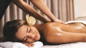 Masajista profesional realizando un masaje relajante en la espalda de una mujer en un ambiente de spa tranquilo