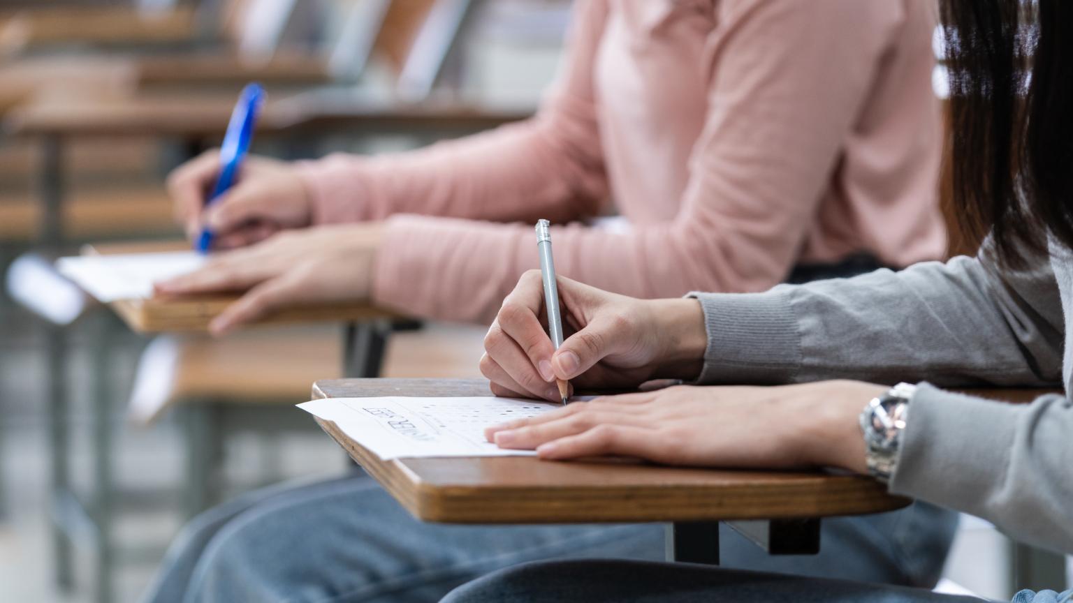 formación en academia de oposiciones con estudiantes realizando examen escrito en aula presencial