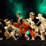 Espectáculo infantil con animación musical en festival familiar durante fiestas patronales con público participando