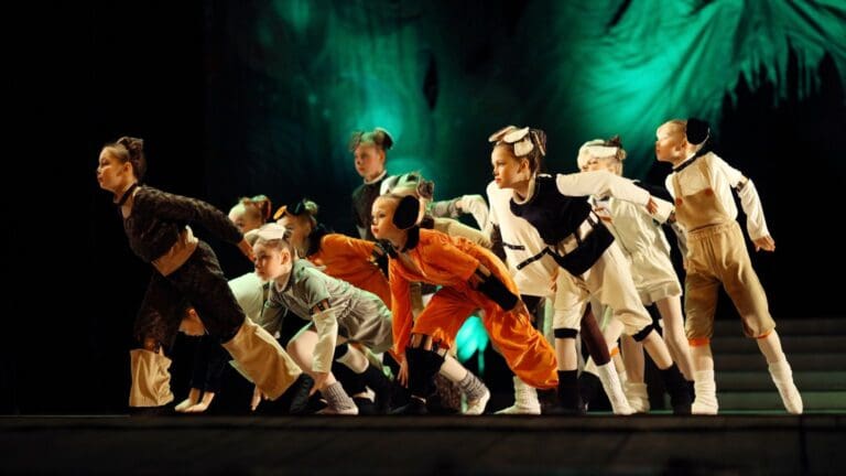 Espectáculo infantil con animación musical en festival familiar durante fiestas patronales con público participando